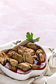 From above ceramic plate with yummy mussels in sauce standing on piece of cloth on gray background