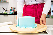 Crop unrecognizable woman decorating cake with glaze while demonstrating skills for colleagues in confectionery