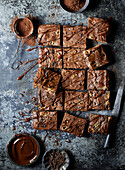 Top view of delicious chocolate brownies with topping and cocoa powder placed on gray surface