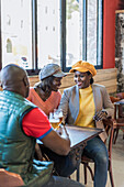 Company of content African American friends gathering at table with beer in bar and talking to each other