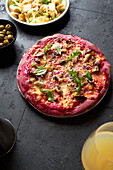 Purple colored rustic pizza with beetroot and vegetarian topping. Top view healthy food recipe