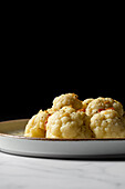 Appetizing cauliflower with bacon drizzled with oil and sprinkled with spices
