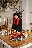 Calm female florist standing at table and arranging bouquet of flowers in creative floristry studio