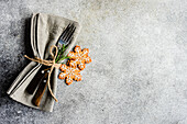 From above table cloth napkin with cutlery near gingerbread cookies setting for Christmas dinner on concrete table on white background