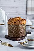 Rustic traditional Christmas panettone cake with raisins on wooden board among luxurious breakfast tableware