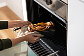 Crop woman taking banana bread out of the oven