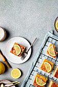 Von oben köstliche hausgemachte quadratische Zitronenkuchenscheiben auf Metallgestell und Teller auf Tisch in Küche