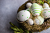 From above nest full of colored eggs as a easter holiday concept on concrete background