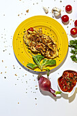 Köstliches Omelett mit gehackter Petersilie auf einem Teller mit sonnengetrockneten Tomaten und rohen roten Zwiebeln auf weißem Hintergrund