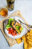 Gegrilltes Lachssteak mit Gemüse, serviert auf einem fischförmigen Teller und mit einem Glas Weißwein serviert