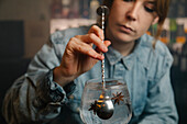 Cropped soft focus of focused female barkeeper adding star anise into wineglass with alcoholic gin and tonic cocktail during work in bar