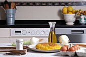 Appetizing traditional Spanish omelette placed on table with eggs and onion in domestic kitchen