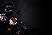 From above of appetizing healthy breakfast consisting of yogurt fresh figs and blackberries sprinkled with seeds and nuts placed on black table