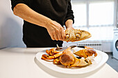 Crop anonymous person with pieces of delicious crab on plate on white table in light kitchen at home