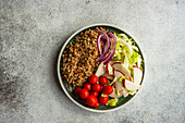 From above bowl with buckwheat and vegetables served on concrete grey table