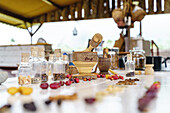 Hölzerne Mörser und Stößel gegen Kaffee Beeren und Bohnen auf dem Tisch auf unscharfen Hintergrund von Steinplatte und Korb platziert