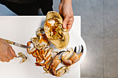 Top view of crop anonymous person with pieces of delicious crab on plate on white table in light kitchen at home