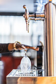 Unrecognizable crop black barman rising glass with water before serving drink in bar