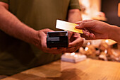 Cropped unrecognizable woman using credit card to pay for goods to vendor in zero waste grocery store