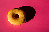 Draufsicht auf einen klassischen Donut ohne Deckel auf rosa Hintergrund