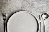 Minimalistisches graues monochromes Tafelservice mit Teller und Besteck