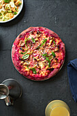 Purple colored rustic pizza with beetroot and vegetarian topping. Top view healthy food recipe