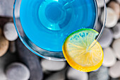 Glass of blue kamikaze drink on stones in modern style