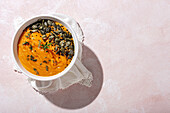 Top view of appetizing healthy pumpkin puree with seeds and seasoning served in white ceramic bowl on table in daylight