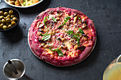 Lila gefärbte rustikale Pizza mit Roter Bete und vegetarischem Belag. Ansicht von oben gesundes Essen Rezept