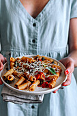 Close up view of cropped woman holding a plate with delicious Pasta alla Puttanesca