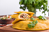 Delicious Colombian patty filled with minced meat on light background stuffed with ground beef and pork with chopped spring onion and fresh coriander on wooden table