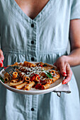 Close up view of cropped woman holding a plate with delicious Pasta alla Puttanesca