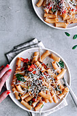 Draufsicht auf ein köstliches Gericht mit Makkaroni-Pasta alla Puttanesca auf einem grauen, rustikalen Tisch