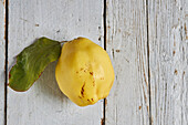 Draufsicht auf eine frische, ganze, saure, gelbe Zitrone auf weißem Holzhintergrund