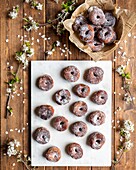 Top view of appetizing lent donuts arranged on white board in wooden table with flowers