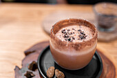 From above glass cup of traditional Mexican Champurrado drink placed on wooden slab on cafe table