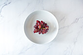 From above of bunch of sweet pink grape served on plate on white background