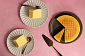 Top view of delicious cotton cheesecake served on plates near spatula on pink background