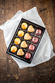 Draufsicht auf süße bunte Schokoladenbonbons in einer Schachtel auf einem Holztisch