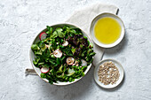 Top view of fresh healthy vegetable salad in bowl served on table with olive oil and sunflower seeds