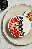Top view of delicious healthy breakfast bowl with white yogurt and fresh strawberries and blueberries with granola
