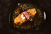 Draufsicht auf leckeren French Toast mit Baiser-Milch-Eiskugel, bedeckt mit süßer Beerensauce auf einem Teller mit Gewürzen in einem Restaurant auf dunklem Hintergrund