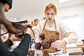 Crop anonymous photographer with photo camera against blogger with muffins in baking cups at home