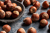 From above bunch of whole ripe hazelnuts in bowl and on marble table