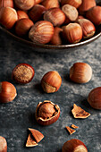 From above bunch of ripe hazelnuts in bowl and shells on marble table