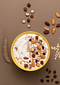 Joghurt von oben mit Haferflocken und getrockneten Nüssen auf braunem Hintergrund