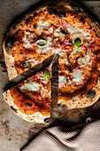 Draufsicht auf eine leckere Pizza mit Käse und Basilikum auf einer verbrannten Oberfläche