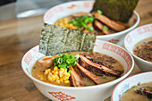 Stockfoto von leckeren Ramen-Suppen mit gekochtem Ei und Fleisch in einem japanischen Restaurant, bereit zum Servieren