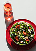 From above tuna salad with onion and tomatoes served on red plates on white background