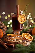 Glühwein oder Weihnachtspunsch, serviert in einem Glasbecher mit getrockneten Orangenscheiben